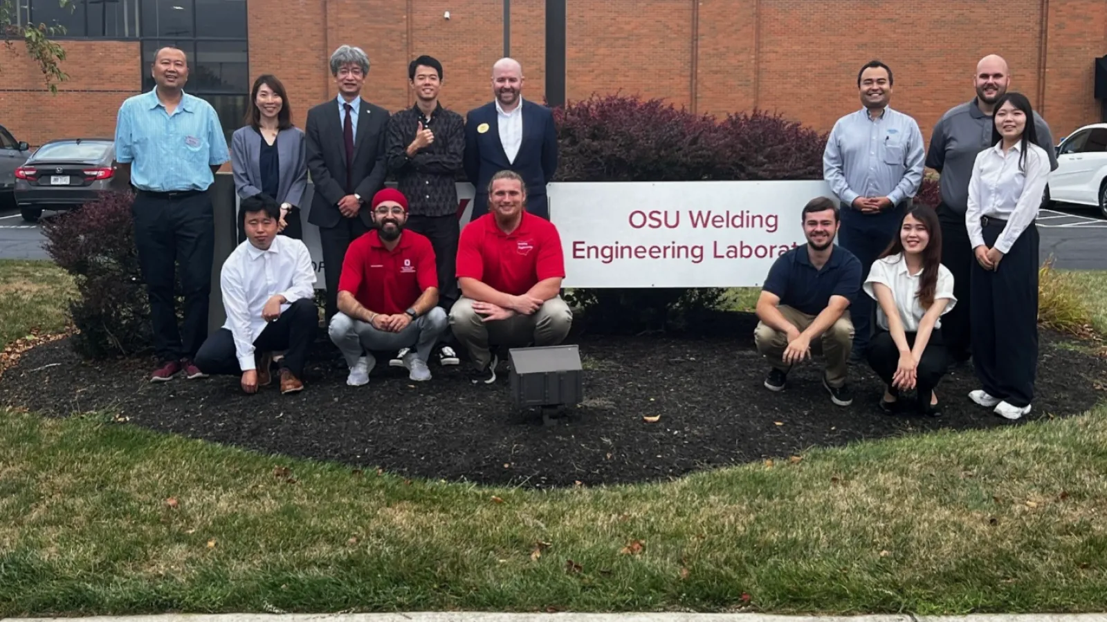 Group of people posing in front of a sign that reads "OSU Welding Engineering Laboratory." 