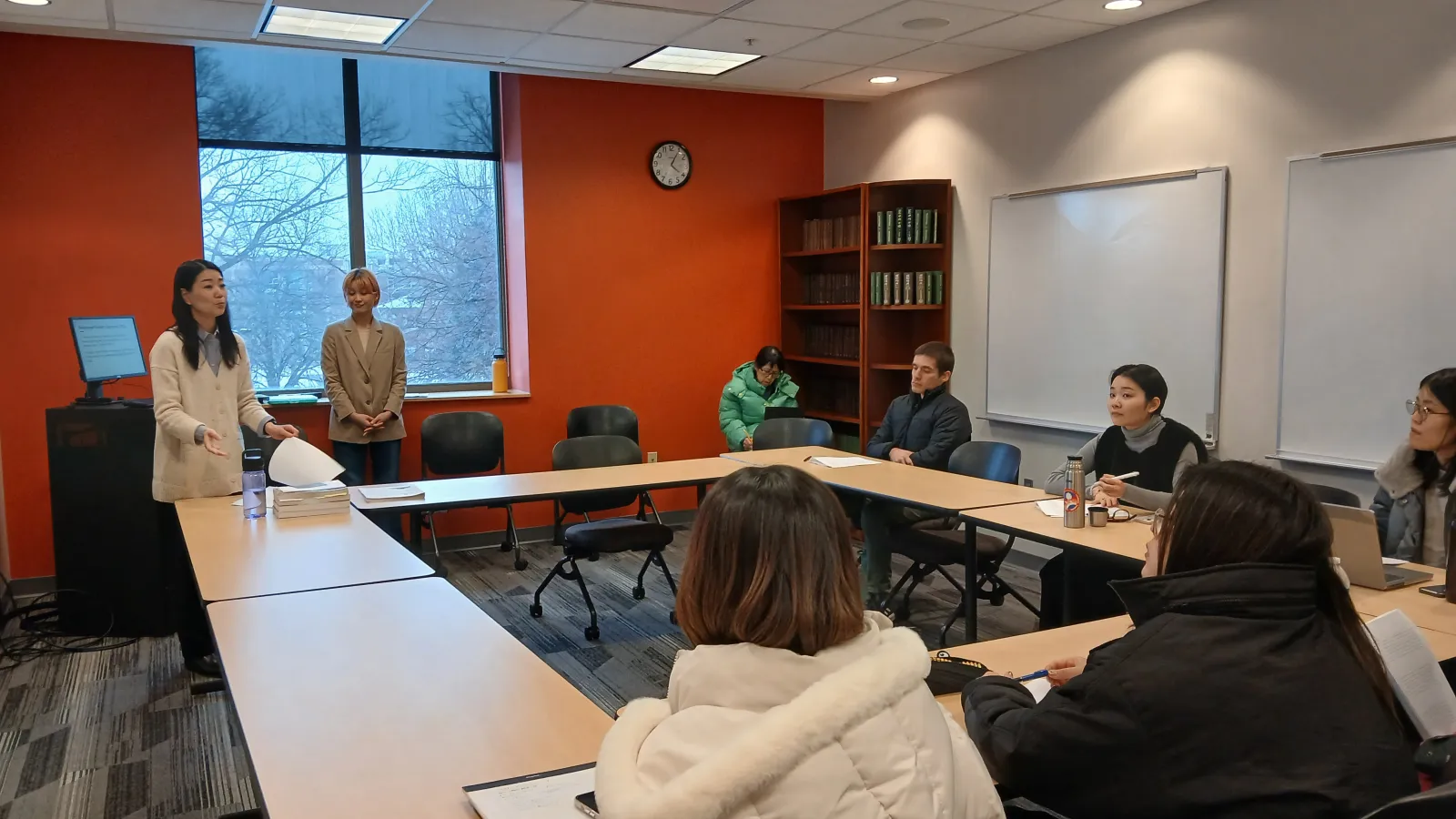 Several people seated at a table, actively participating in a classroom discussion.