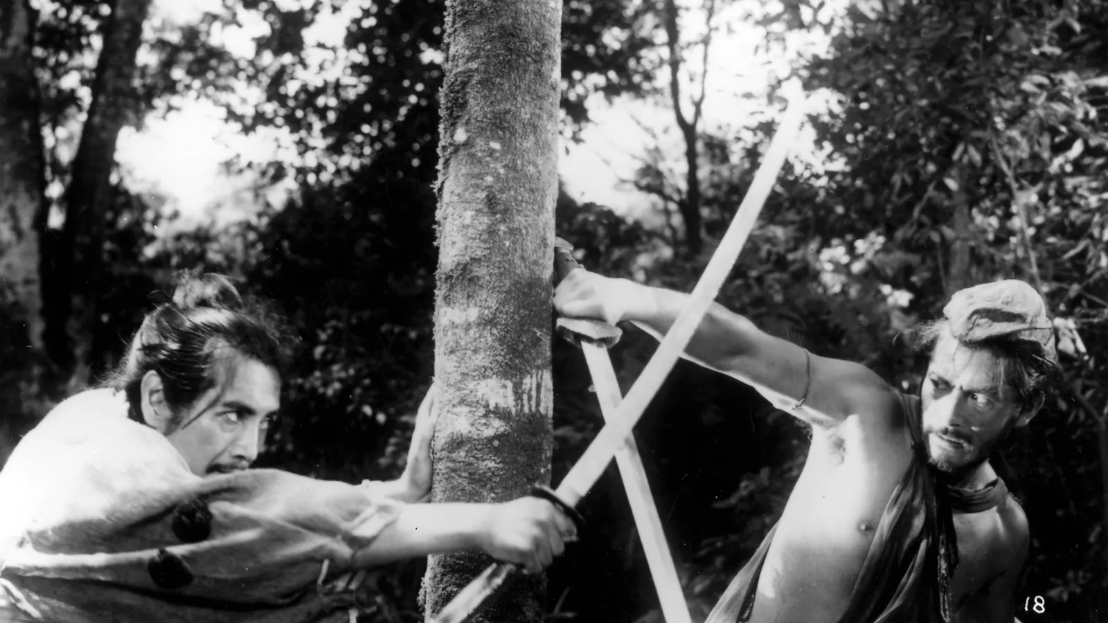A scene Rashōmon where two men are fighting with katanas. One wears traditional clothing and the other wears more loose minimal clothing. 