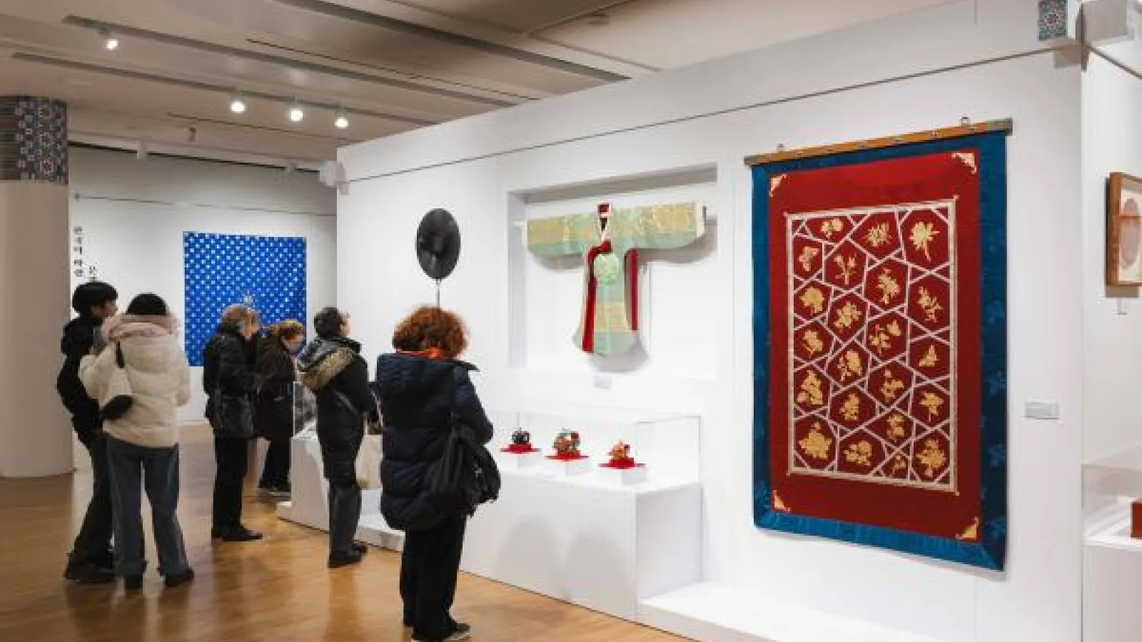 A group of people observing various artworks displayed in a museum gallery. 