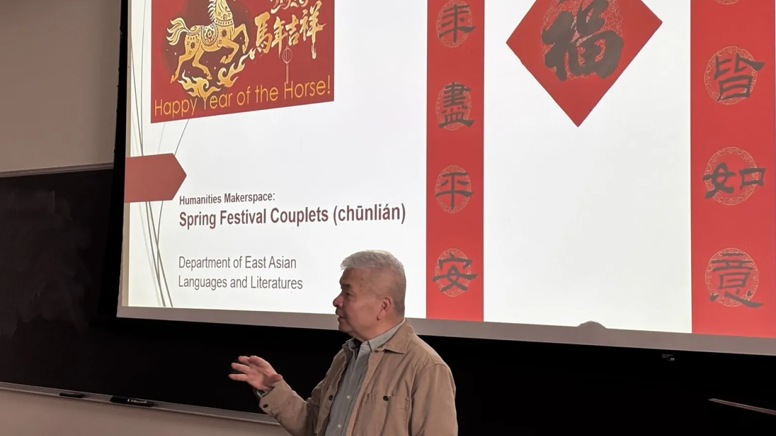 A man presenting in front of a large screen, engaging the audience with visual aids and gestures