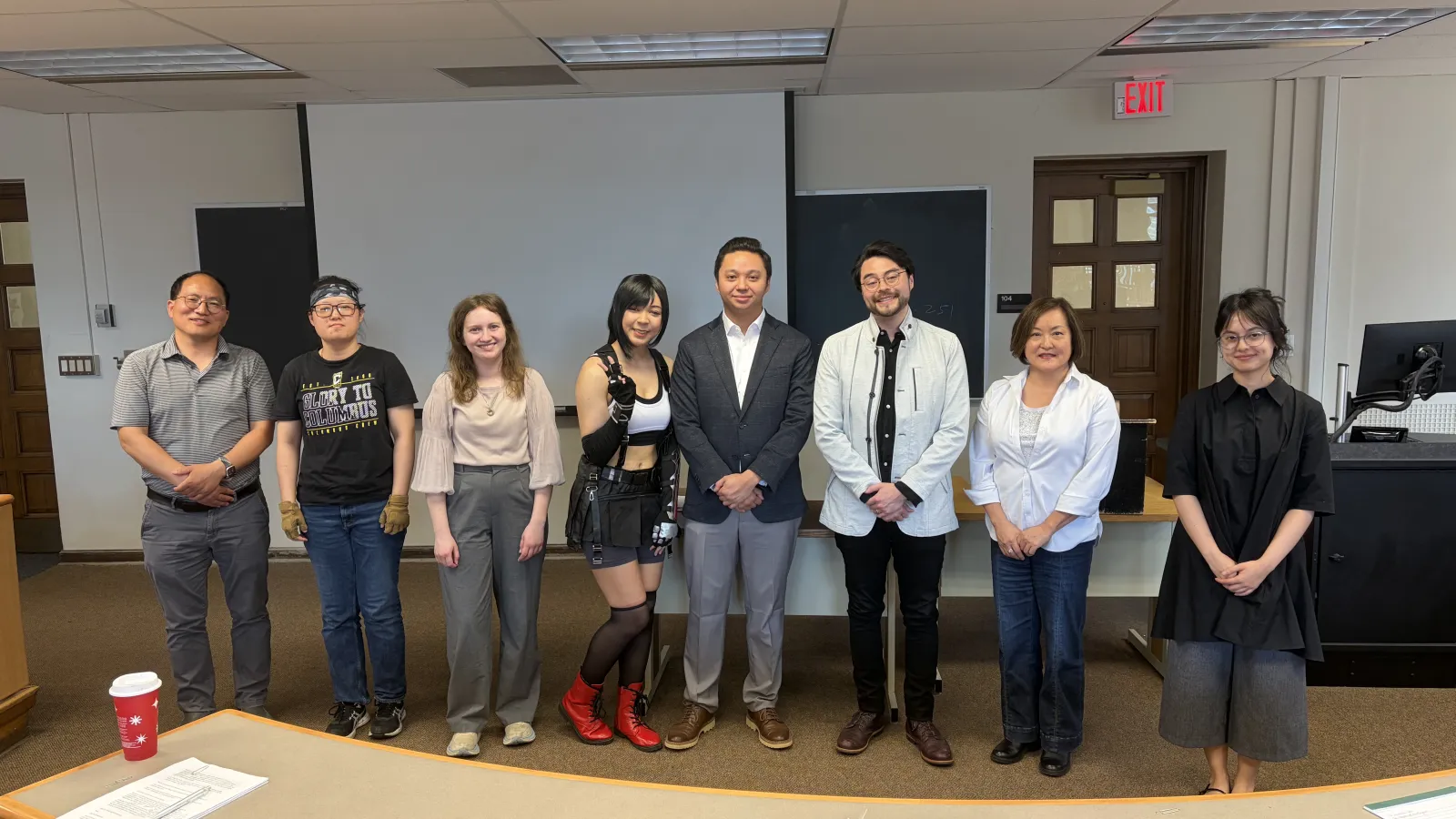 A diverse group of people standing together in front of a conference room, engaged in conversation.  