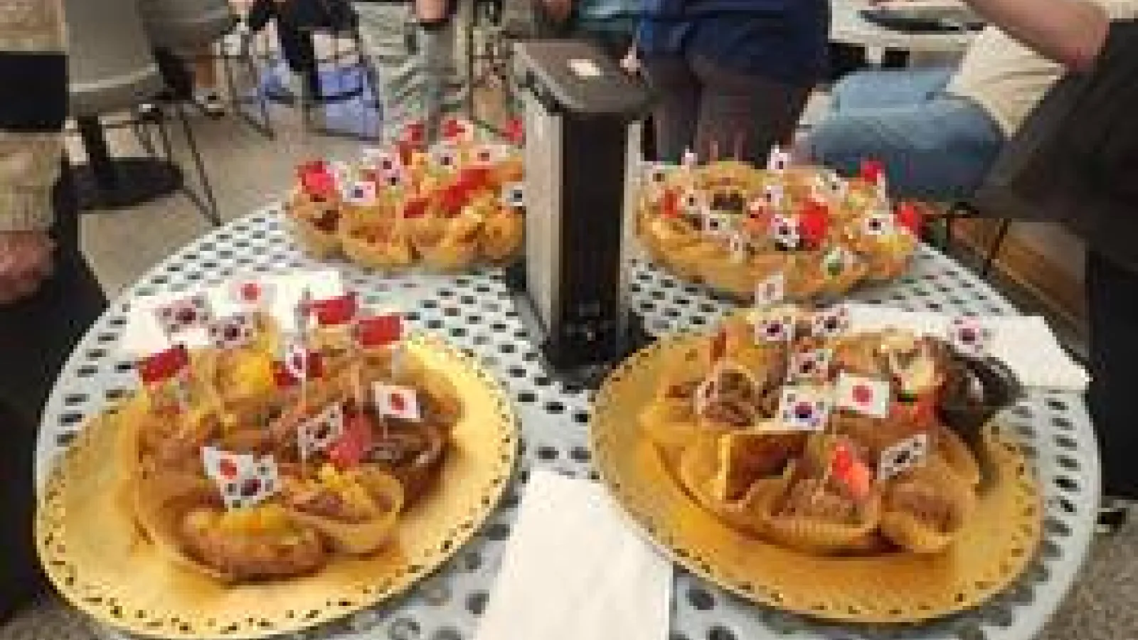 A table laden with food, surrounded by people engaged in conversation and enjoying the meal together.