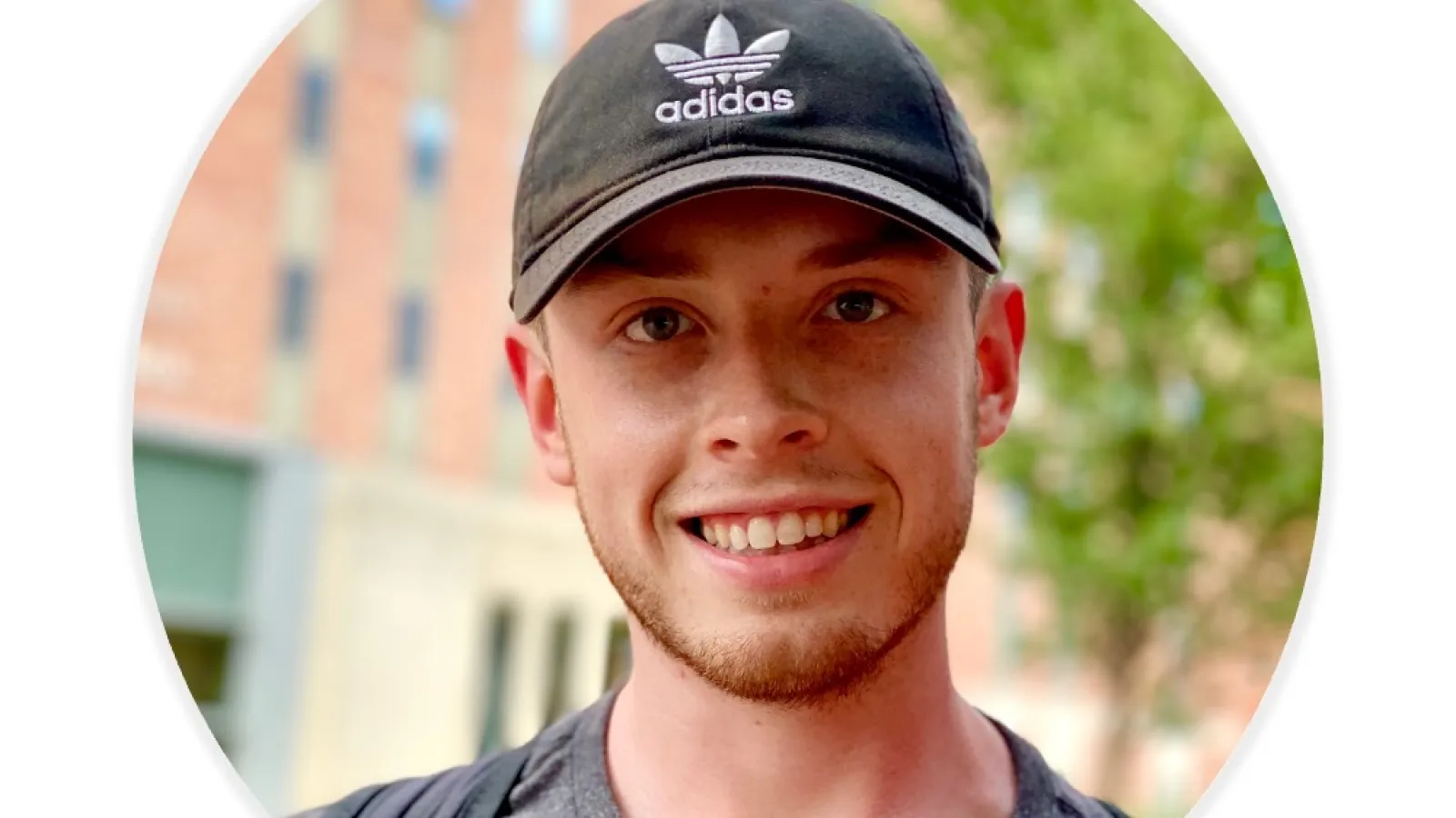 Young man wearing a dark baseball cap looking at the camera
