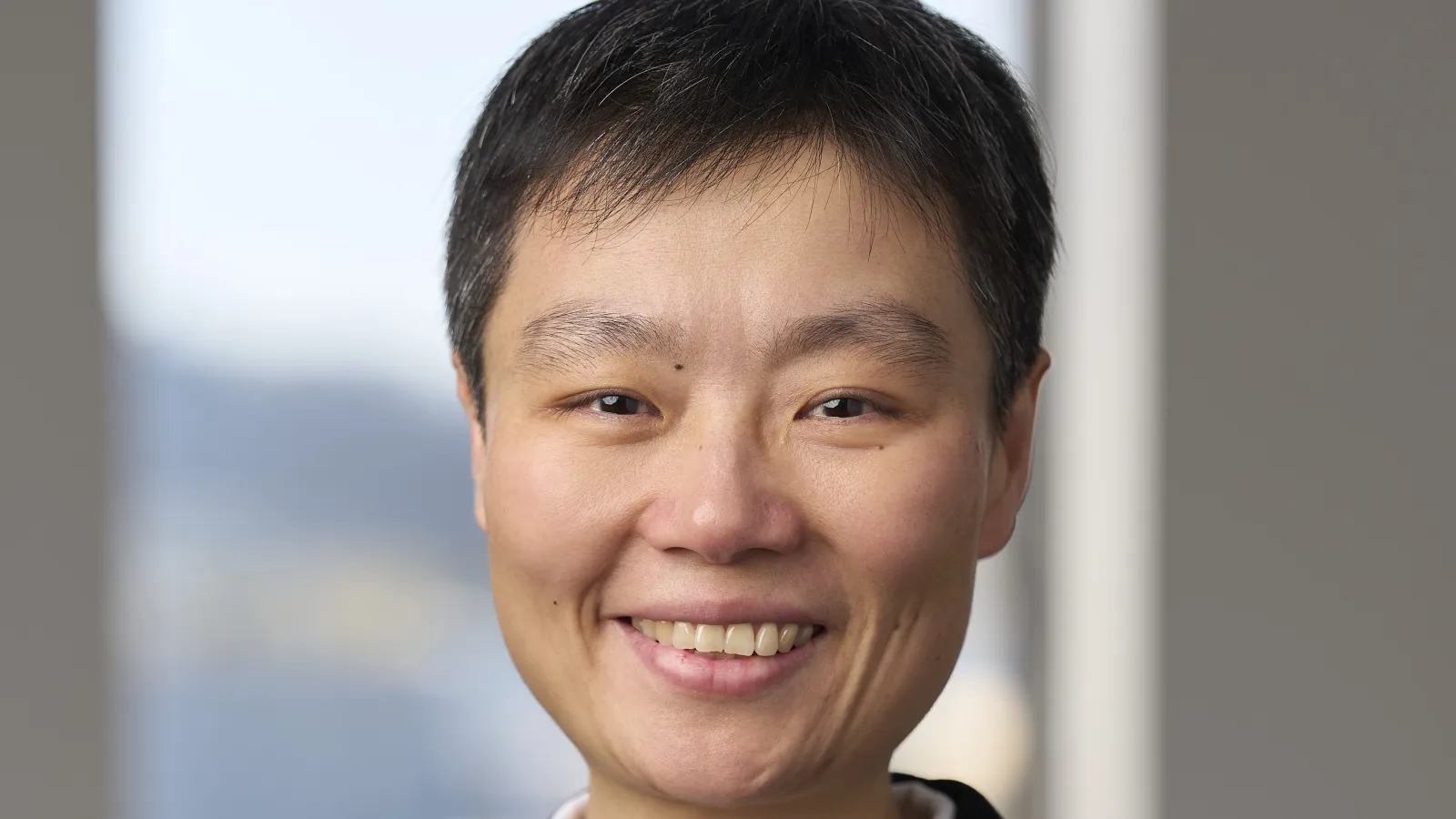 Woman with short dark hair and business attire smiles at camera