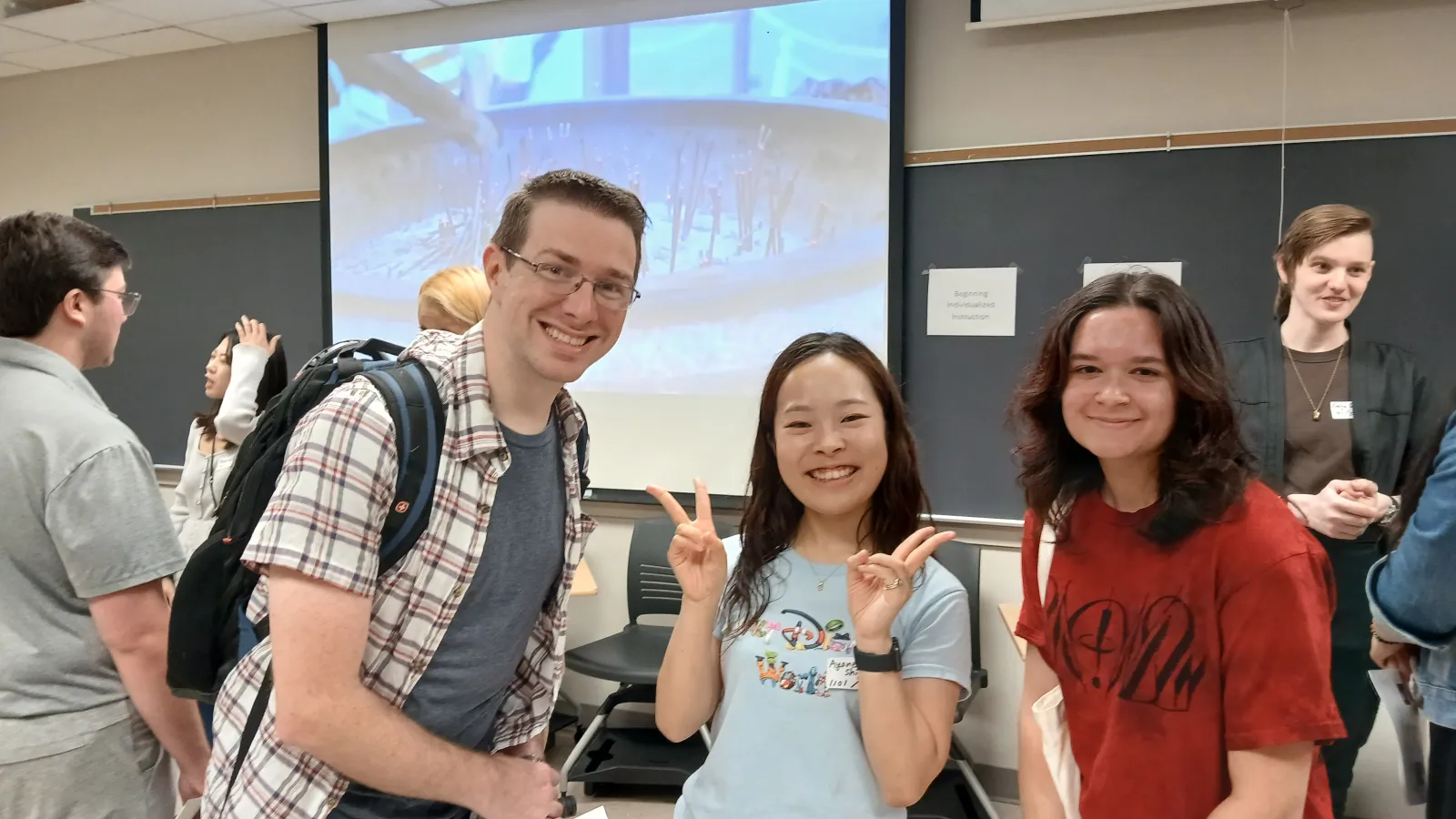 1 man (left) and 2 women posed with smiles in a classroom
