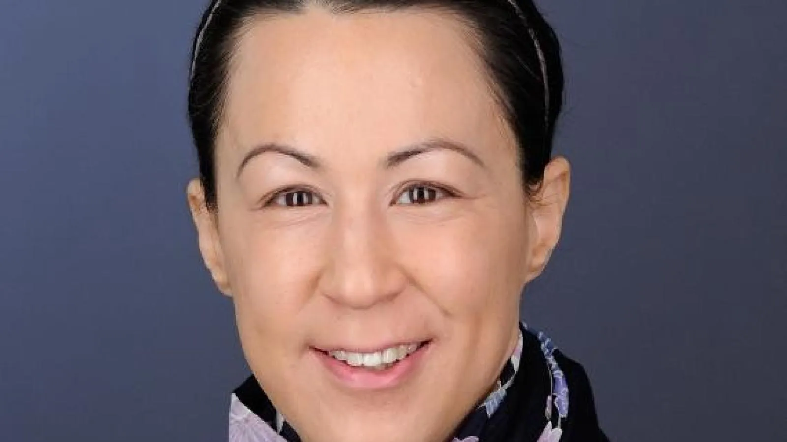 Woman with short hair and a dark scarf looking at camera with a smile