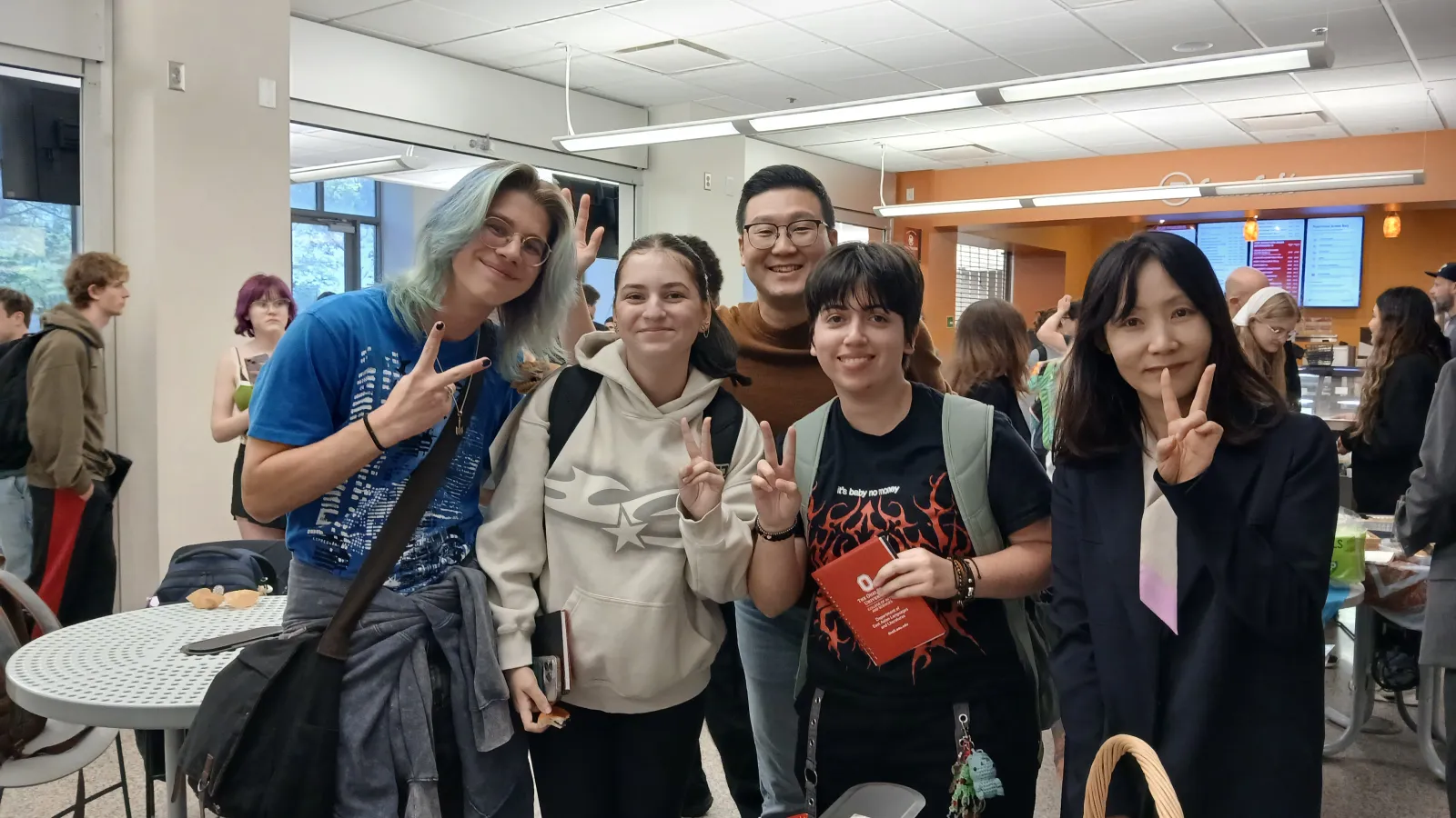 Five people looking into the camera and holding up peace sign hand gestures