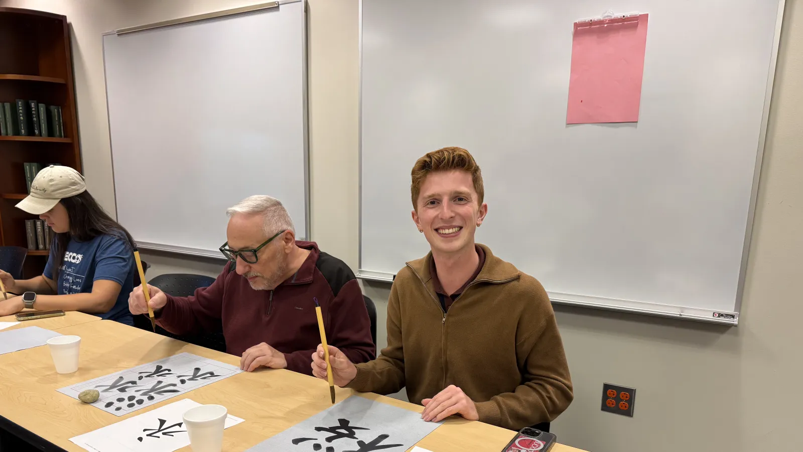 Young man doing caligraphy with a brush and paper