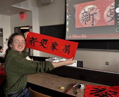 A woman holds a red sign featuring Chinese characters, conveying a message or announcement.