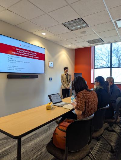 1. A group of diverse individuals seated around a table engaged in discussion in a well-lit room.  