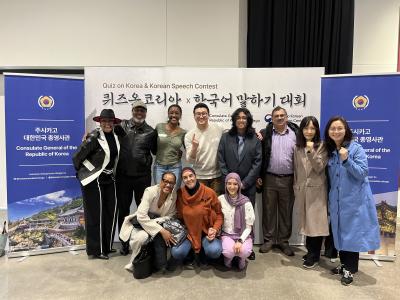 A group of people smiling and posing together in front of a colorful banner at an event.  