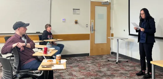 Woman with dark hair speaks at the front of a classroom