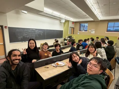 A group of people seated at tables in a classroom, engaged in discussion and learning activities.  
