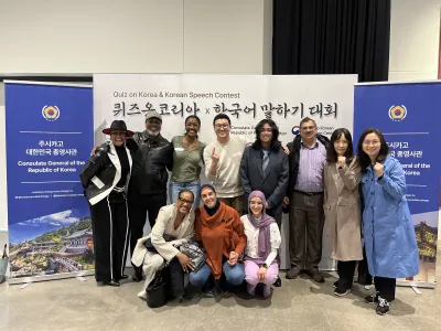 A group of people smiling and posing together in front of a colorful banner at an event.  