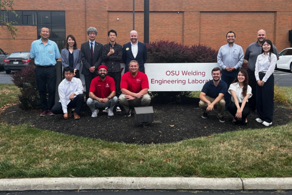 Group of people posing in front of a sign that reads "OSU Welding Engineering Laboratory." 