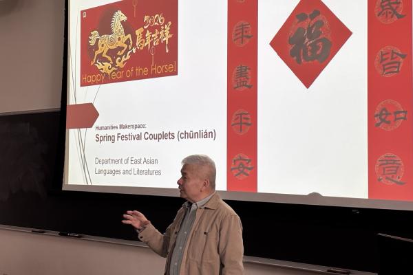 A man presenting in front of a large screen, engaging the audience with visual aids and gestures