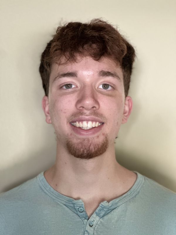 Portrait of a young man with short, curly brown hair and a light green Henley shirt