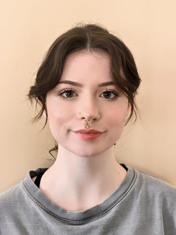 Smiling dark-haired woman wearing a gray shirt and nose ring