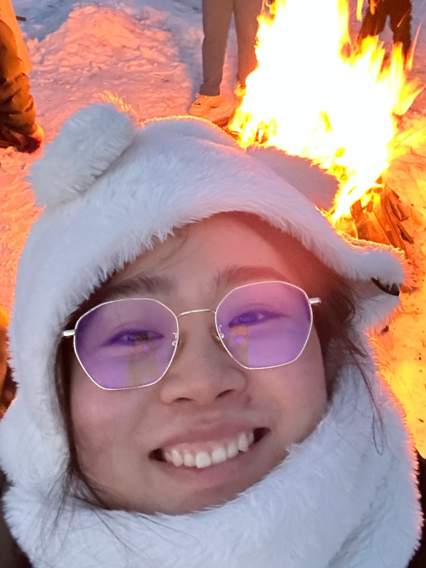 Smiling Woman with glasses, standing in front of a bonfire