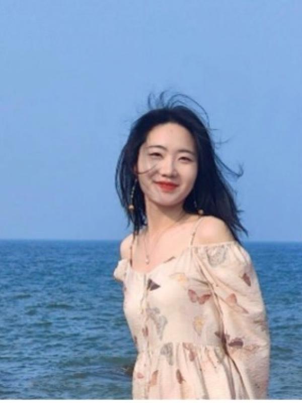 Smiling woman in white dress with ocean behind her