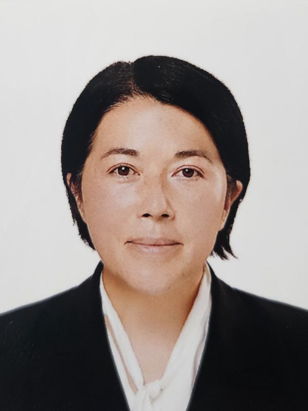 A professional woman in a suit and tie confidently gazes at the camera