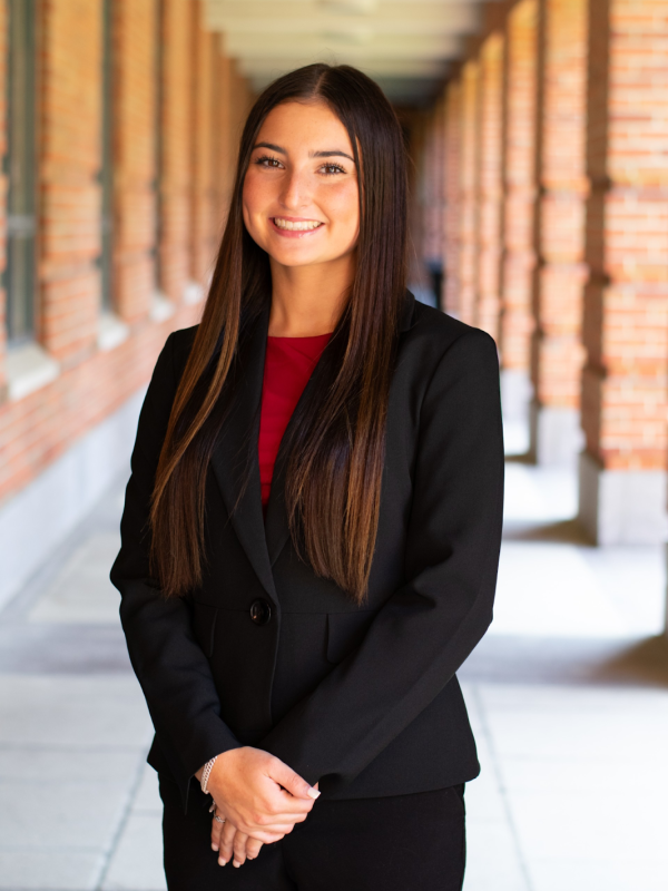 Smiling woman with dark hair standing in front of a row of brick columns
