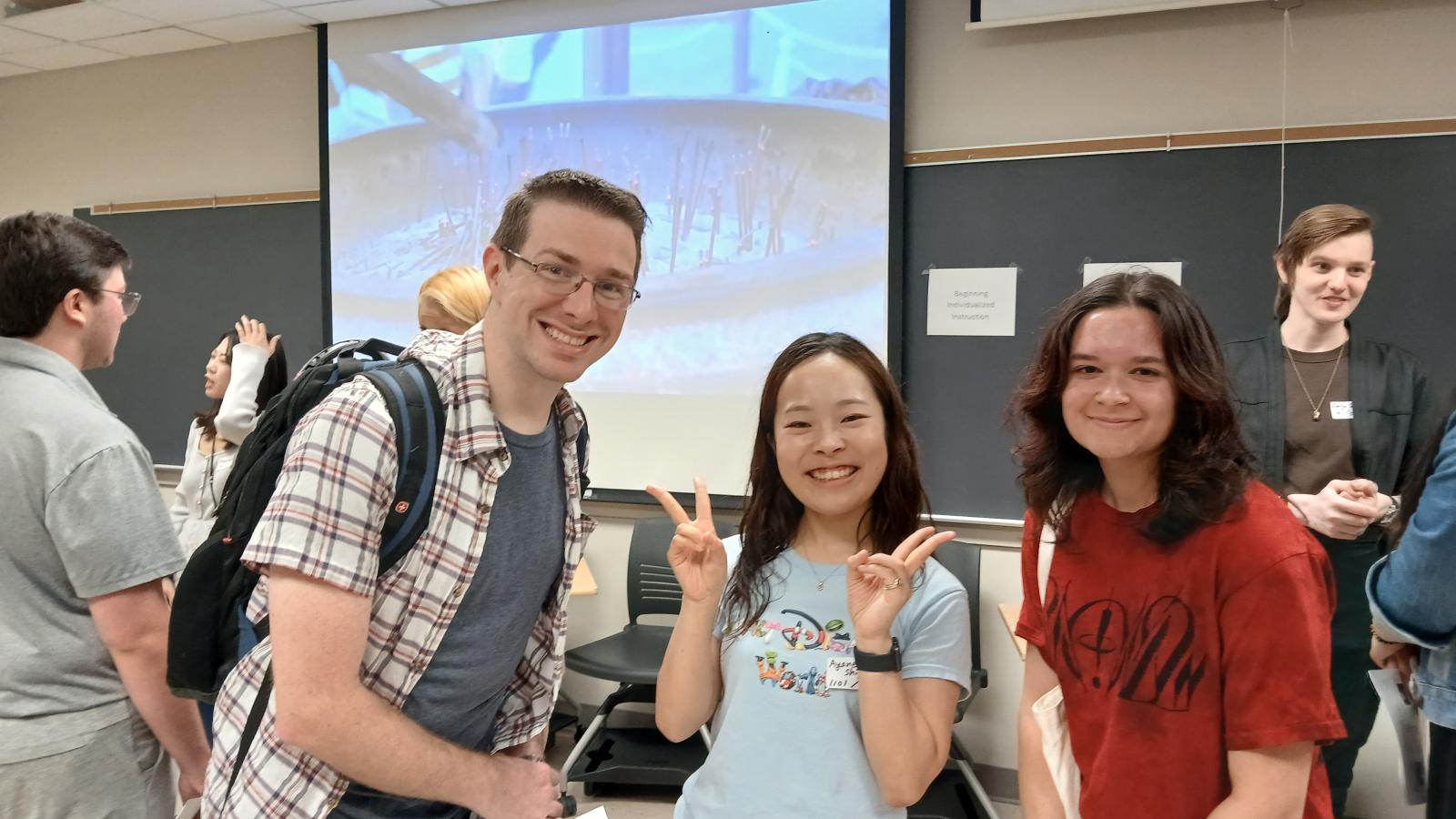 1 man (left) and 2 women posed with smiles in a classroom