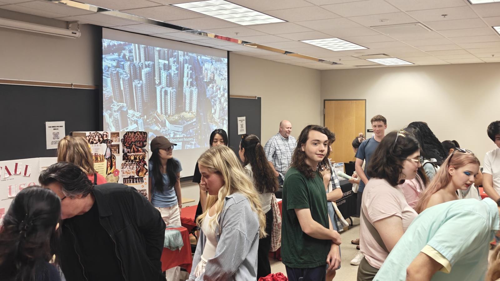 large group of people standing around a classroom and talking together