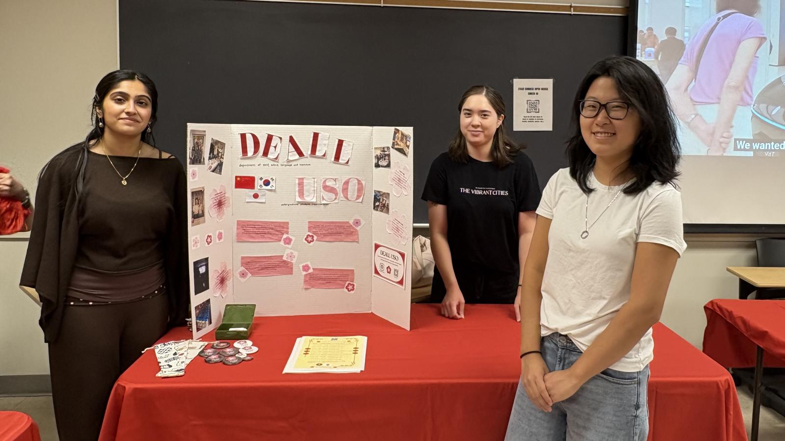 3 students standing in front of a posterboard titled "DEALL USO"