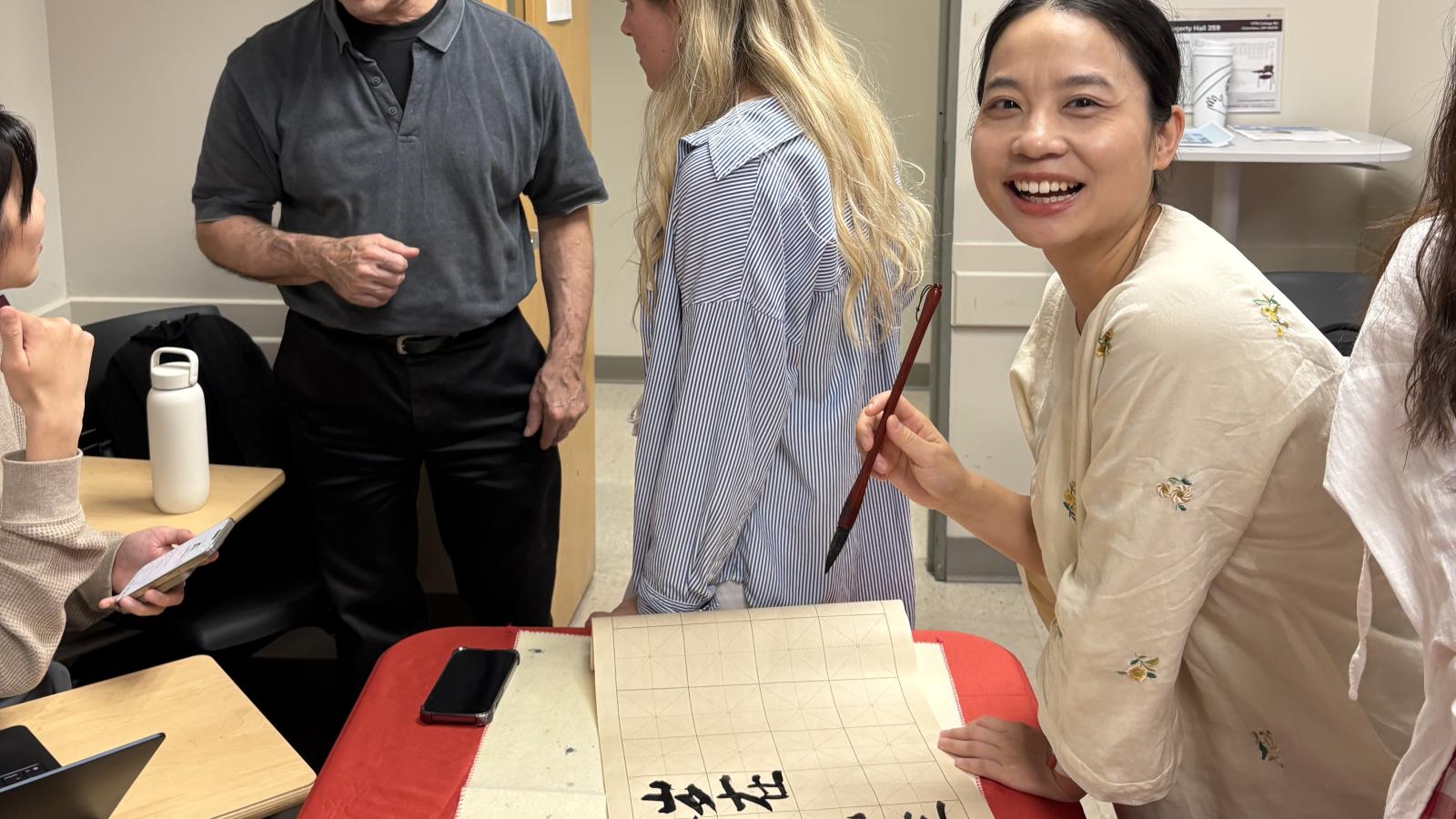 Woman holding a caligraphy brush and smiling