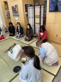 a group of people sitting on a tatami mat and enjoying tea
